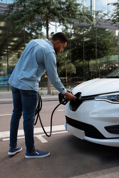 Volledig geschoten man die elektrische auto oplaadt