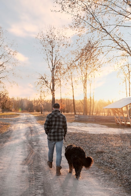 Gratis foto volledig geschoten man die met hond buiten loopt