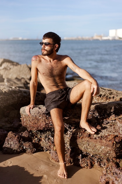 Gratis foto volledig geschoten man met harige borst aan zee