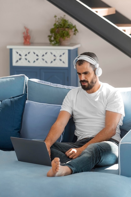 Volledig geschoten man met laptop op de bank