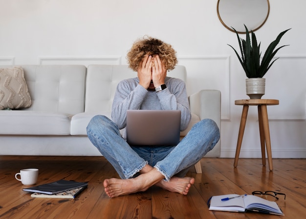 Volledig geschoten man met laptop op de vloer