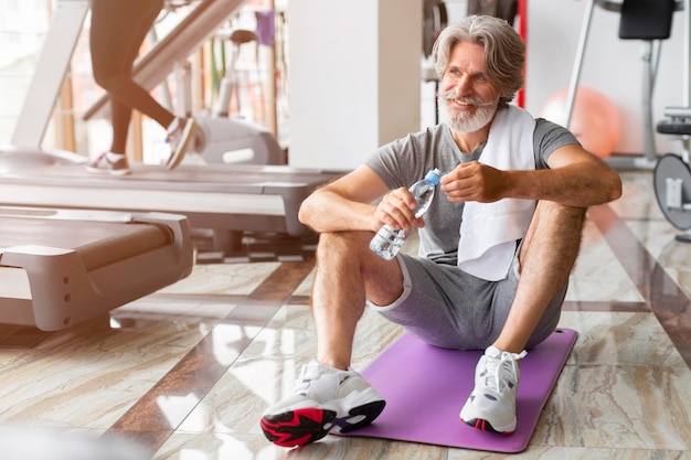 Volledig geschoten man zittend op yoga mat