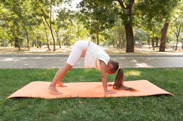 Volledig geschoten meisje dat yoga op mat doet