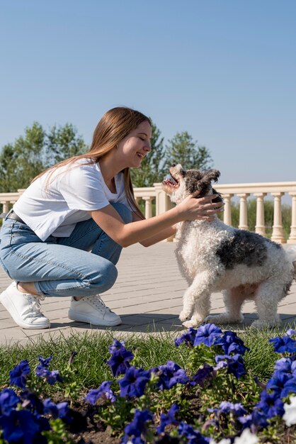 Volledig geschoten meisje en schattige hond buitenshuis
