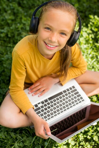 Volledig geschoten meisje met laptop en koptelefoon
