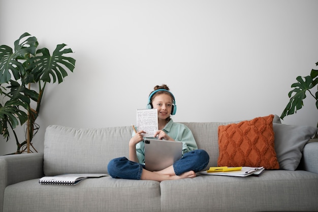 Gratis foto volledig geschoten meisje met tablet en hoofdtelefoon thuis