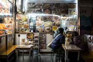 Gratis foto volledig geschoten mensen die eten in een japans straatvoedselrestaurant