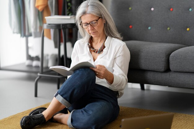 Volledig geschoten oude vrouw die op de vloer leest