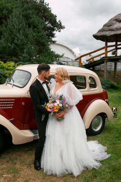 Volledig geschoten paar poseren met vintage auto