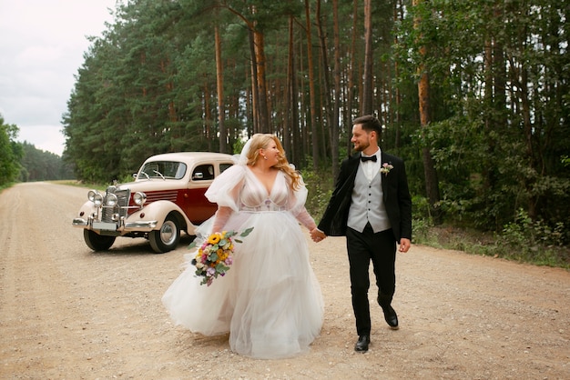 Gratis foto volledig geschoten paar poseren met vintage auto