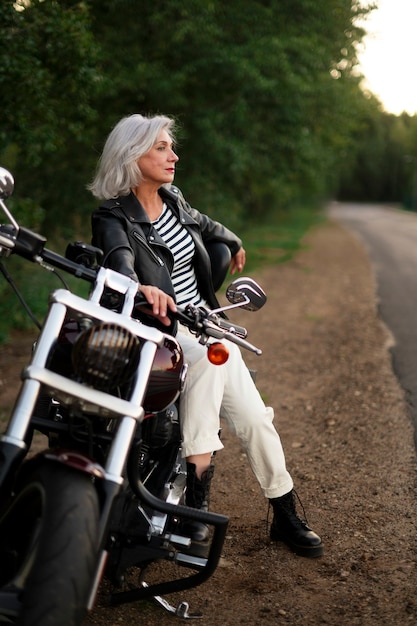 Volledig geschoten senior vrouw met motorfiets