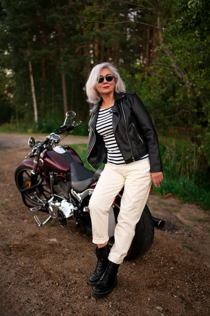 Gratis foto volledig geschoten senior vrouw met motorfiets