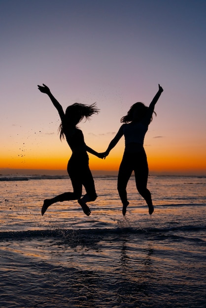 Gratis foto volledig geschoten silhouetten van mensen die springen bij zonsondergang