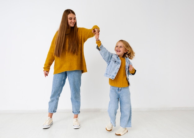 Gratis foto volledig geschoten smileymoeder en meisje in studio