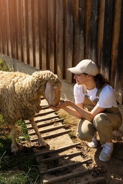 Gratis foto volledig geschoten smileyvrouw die schapen voert