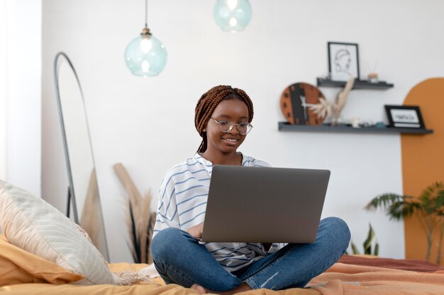 Volledig geschoten smileyvrouw ontspannen met laptop