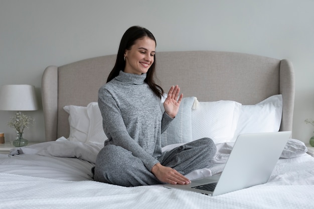 Volledig geschoten smileyvrouw zittend op bed