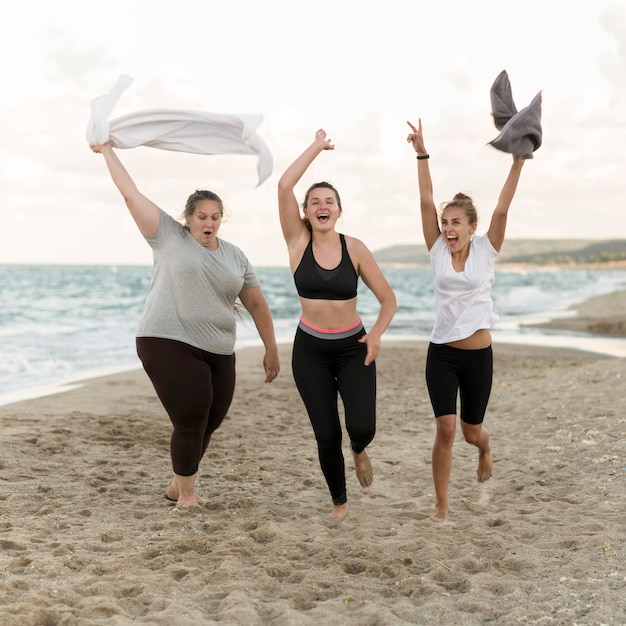 Gratis foto volledig geschoten vrienden die op strand lopen