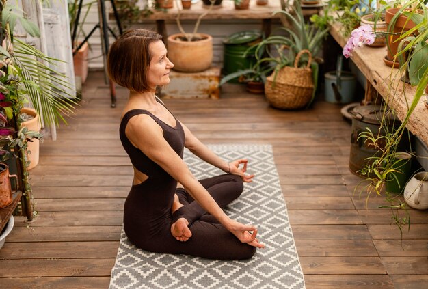 Volledig geschoten vrouw binnenshuis op yogamat