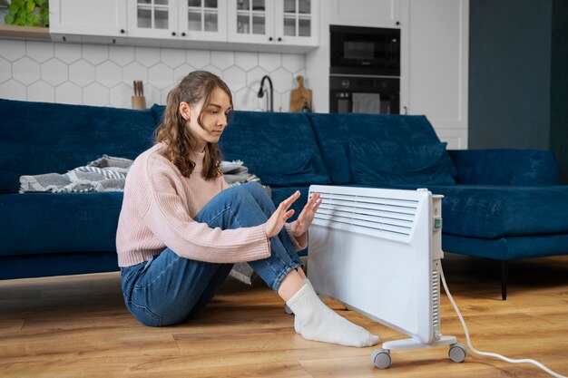 Volledig geschoten vrouw die bij de verwarming zit