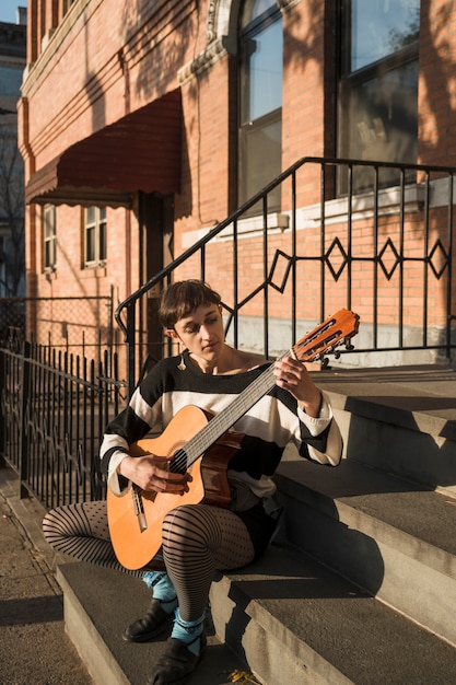 Volledig geschoten vrouw die gitaar speelt op trappen