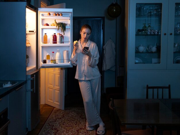 Volledig geschoten vrouw die 's nachts snacks heeft