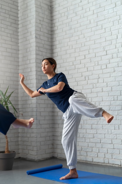 Gratis foto volledig geschoten vrouw die tai chi binnenshuis beoefent