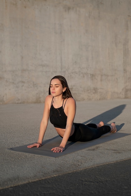 Gratis foto volledig geschoten vrouw die yoga op mat doet