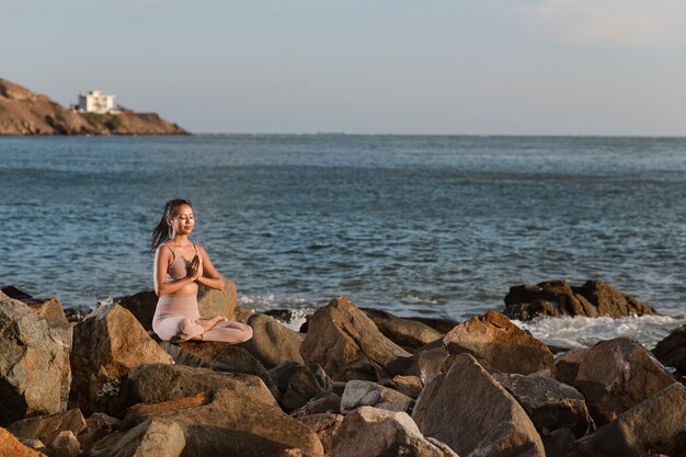 Volledig geschoten vrouw die yoga op rotsen doet