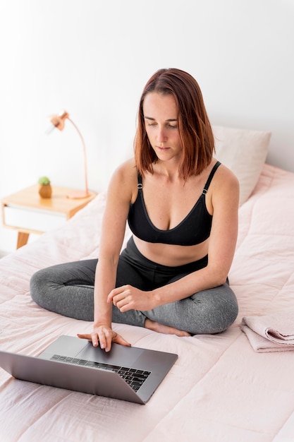 Volledig geschoten vrouw met laptop in bed