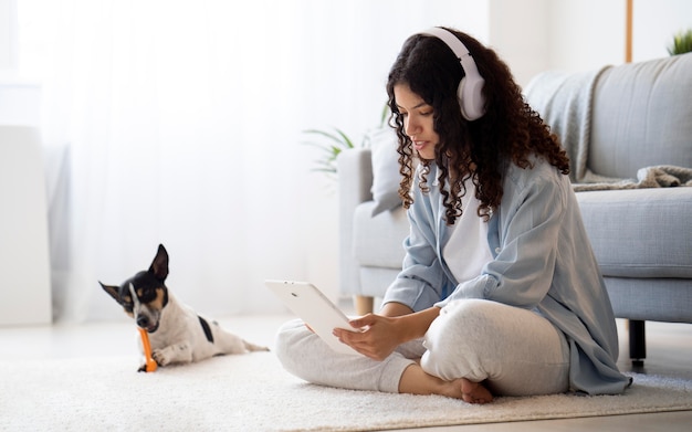 Gratis foto volledig geschoten vrouw zittend op de vloer met tablet