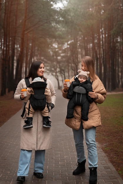 Gratis foto volledig geschoten vrouwen die baby's in dragers houden