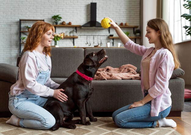 Volledig geschoten vrouwen en hond die met stuk speelgoed spelen