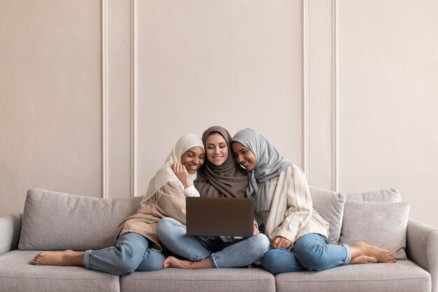 Volledig geschoten vrouwen zittend op de bank met apparaat