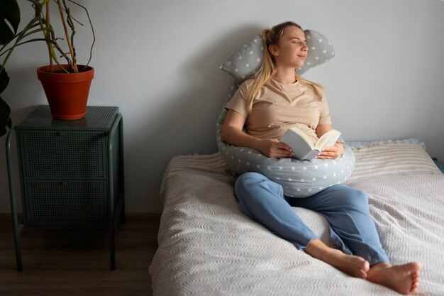 Volledig geschoten zwangere vrouw die borstvoedingskussen gebruikt