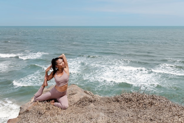 Volledig geschotene smileyvrouw die yoga in openlucht doet