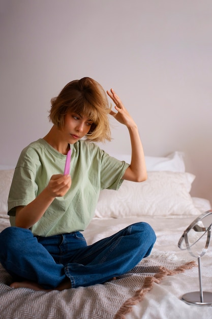 Volledig geschotene vrouw die droge shampoo thuis gebruikt