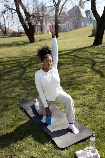 Gratis foto volledig geschotene vrouw die met yogablok uitoefent