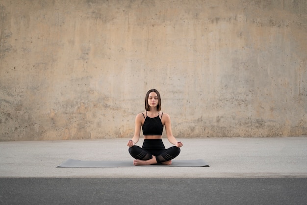 Volledig geschotene vrouw die op yogamat mediteert