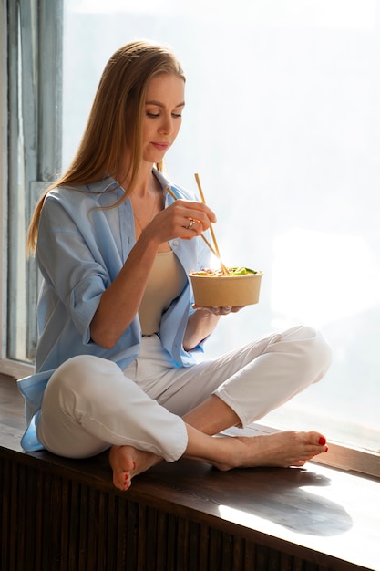 Gratis foto volledig geschotene vrouw die zalmkom eet