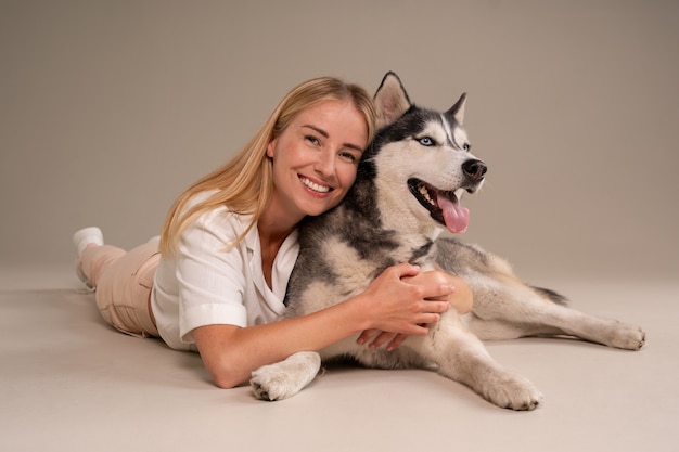 Gratis foto volledig geschotene vrouw met hond in studio