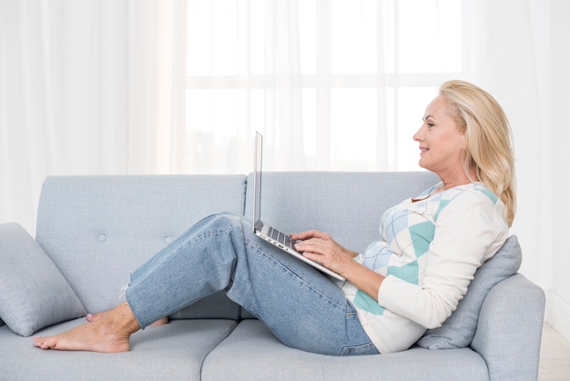 Volledig geschotene vrouw met laptop op de bank