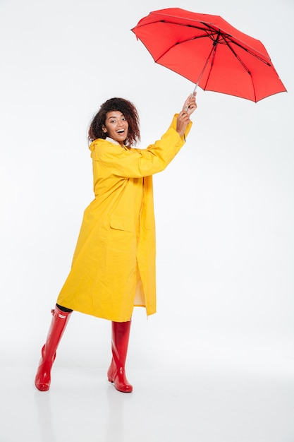 Gratis foto volledig lengtebeeld van zorgeloze afrikaanse vrouw in regenjas