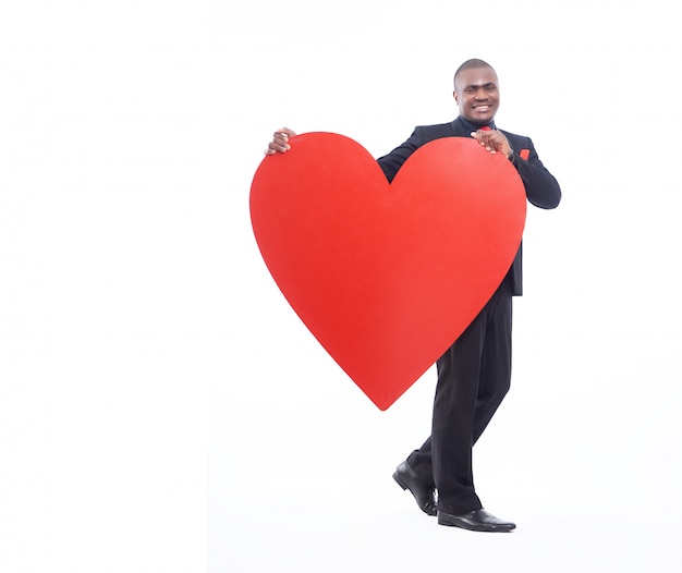 Gratis foto volledig lengteportret van de jonge afrikaanse mens die groot rood hart houdt