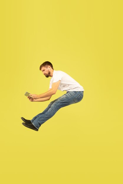 Volledig lengteportret van gelukkige springende mens op gele achtergrond