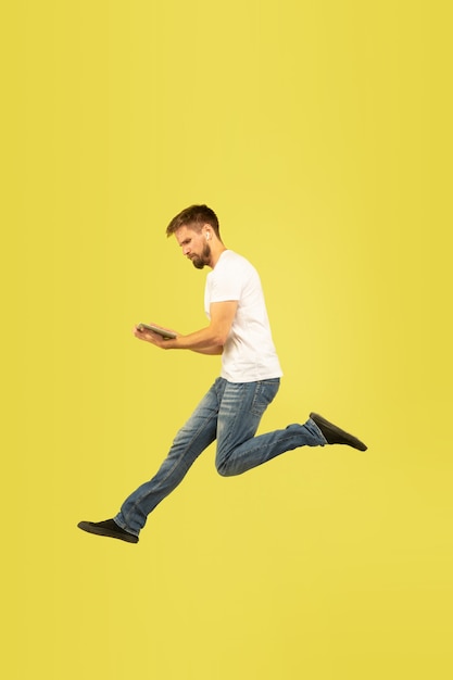 Volledig lengteportret van gelukkige springende mens op gele muur