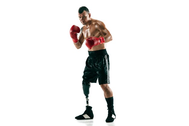 Volledig lengteportret van gespierde sportman met prothetisch been, kopieer ruimte. Mannelijke bokser in rode handschoenen. Geïsoleerd schot op witte muur.