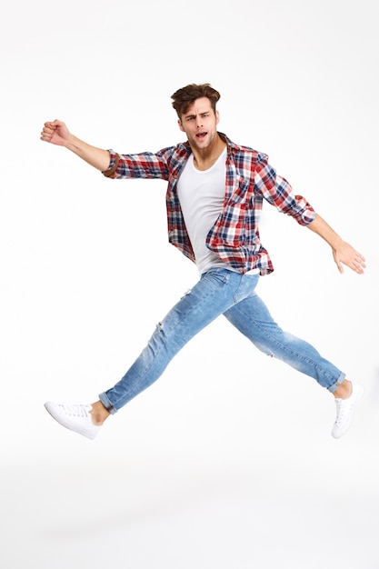 Volledig lengteportret van het toevallige jonge mens springen