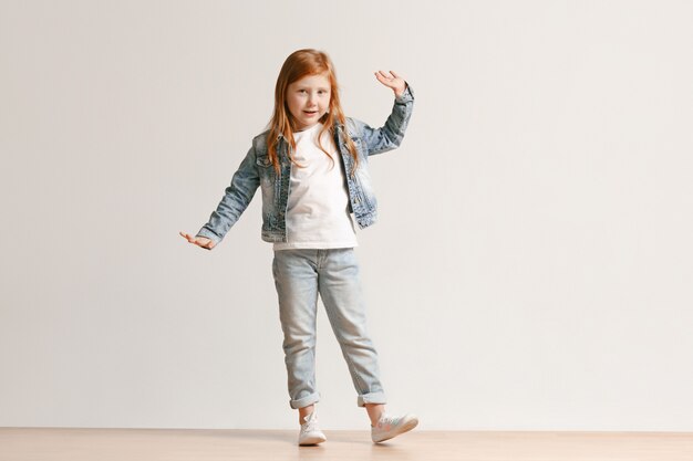 Volledig lengteportret van leuk klein jong geitje in het modieuze jeanskleren glimlachen