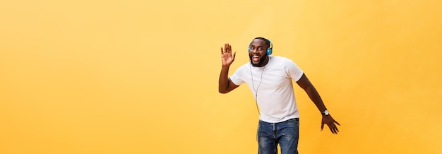 Volledig portret van een kersen jonge Afro-Amerikaanse man die naar muziek luistert met een koptelefoon en d